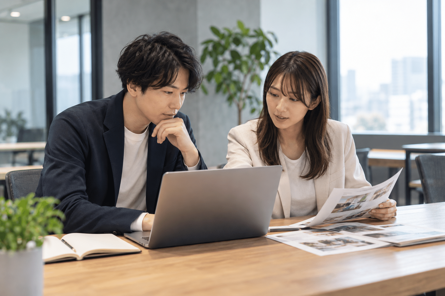 日本人の男女2人が木の机でノートPCを見ながら学習資料を読む
