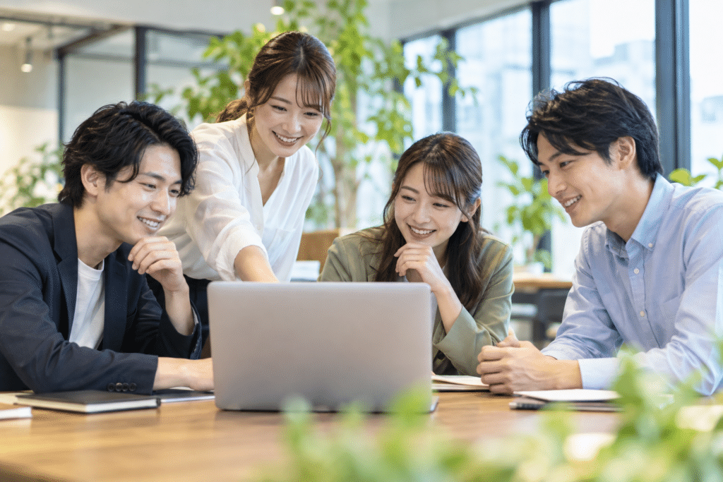 日本人の男女4人が研修スペースでノートPCを見ながら話し合う